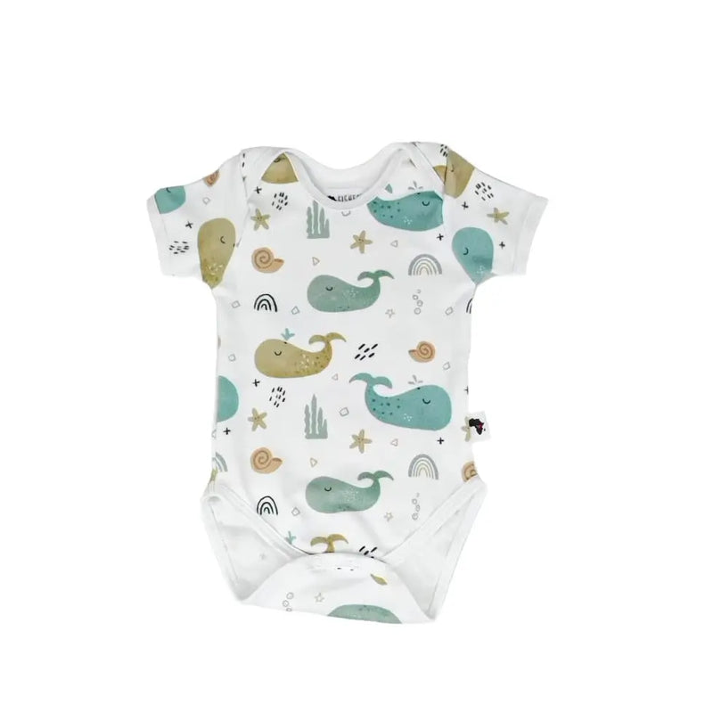 A short-sleeve baby onesie featuring whimsical whale, starfish, and rainbow illustrations on a white background. Made from soft and stretchy cotton-lycra fabric with snap closures for convenience