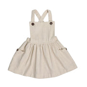 Natural linen dungaree dress with wooden buttons, gathered skirt, and cross-back straps.