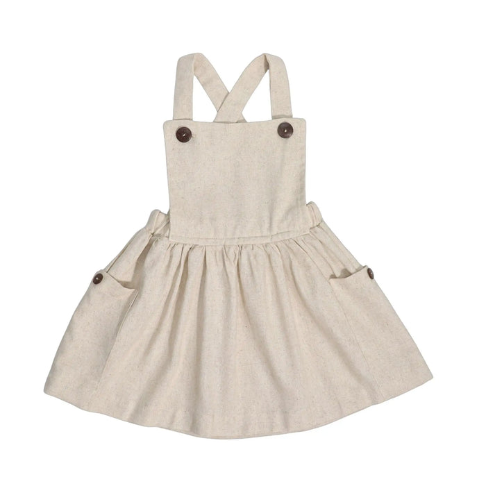 Natural linen dungaree dress with wooden buttons, gathered skirt, and cross-back straps.