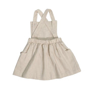 Back of natural linen dungaree dress with wooden buttons, gathered skirt, and cross-back straps.