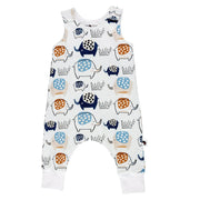Front view of a sleeveless harem-style baby romper in white, featuring a playful elephant print in rust, navy, and soft blue, with shoulder press studs and fold-over ankle cuffs.