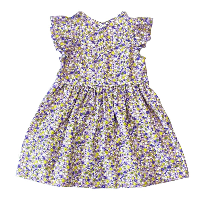 Lightweight sunflower dress in purple ditzy pattern, made from medium-weight cotton fabric, featuring stud buttons and frills around the arms.