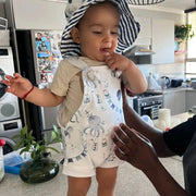 A child standing on a kitchen counter wearing Otto the Octopus Knot Dungarees and Bucket Hat from Baba Fishees