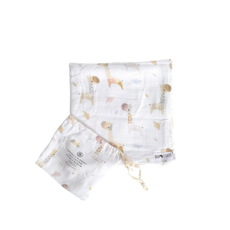 White muslin swaddle blanket with Kameelperd giraffe print in soft beiges and browns, shown with drawstring pouch.