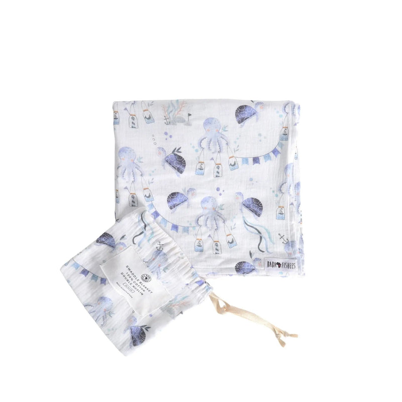 White cotton muslin swaddle blanket with Otto the Octopus ocean print in shades of blue, shown folded with matching pouch.