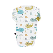 Back view of a white long-sleeve wrap-style baby onesie featuring a whimsical whale print in shades of blue, teal, and mustard, accented with rainbows, starfish, and seashells. Designed with press-stud closures for easy dressing.