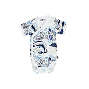 Front view of a white short-sleeve wrap onesie featuring an African sea life print with dolphins, turtles, fish, and coral in shades of blue from BabaFishees.