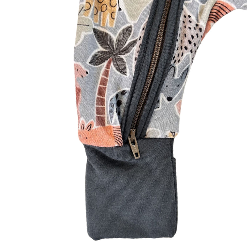 Close-up of a zippered foot with an airforce blue cuff and a printed fabric body featuring safari-style animal and palm tree motifs in beige, gray, orange, and brown.