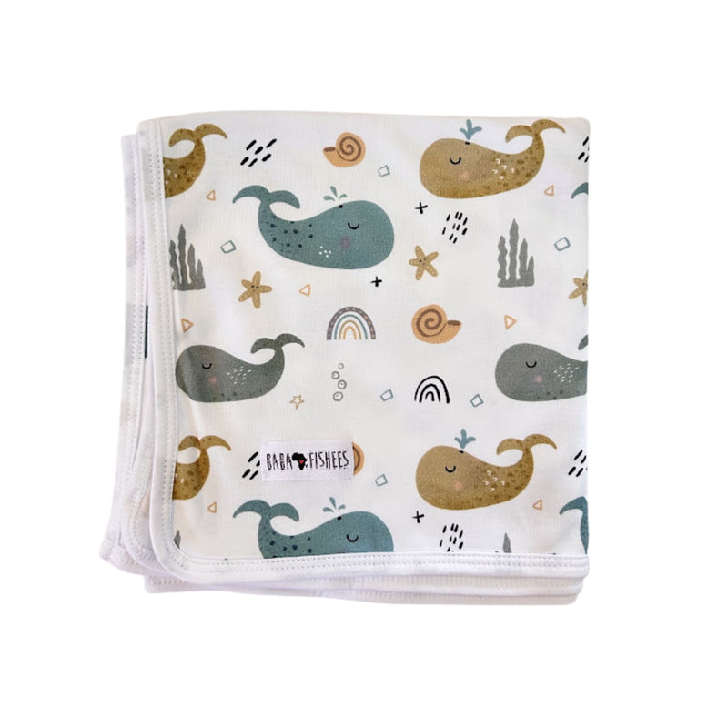 Baby Blanket - Whales on White folded white cotton blanket with blue, grey and mustard whale print.