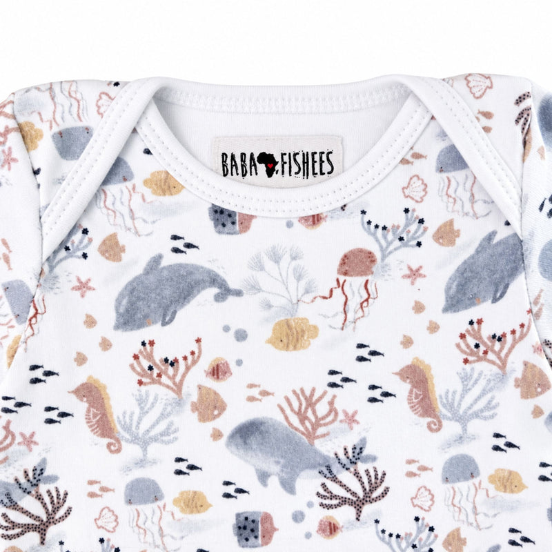 Neckline close-up of short-sleeve Classic Onesie - Finn and Friends showing the white-bound envelope neck, Baba Fishees label and detailed marine print