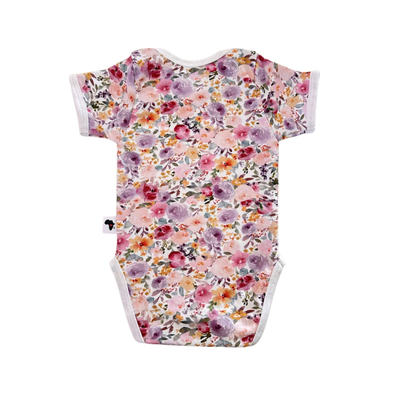 Floral Fantasy short-sleeve baby onesie shown from the back, with an all-over floral print and white-trimmed leg openings
