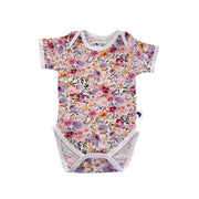 Floral Fantasy short-sleeve baby onesie shown from the front, featuring an envelope neckline, short sleeves and all-over floral print