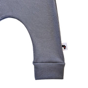 Close-up of a ribbed charcoal grey garment leg with a small white brand tag featuring a black silhouette of Africa with a red heart.