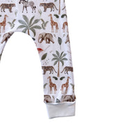 White children's leggings with an all-over safari animal print featuring giraffes, zebras, elephants, and palm trees, finished with a solid white ribbed cuff.