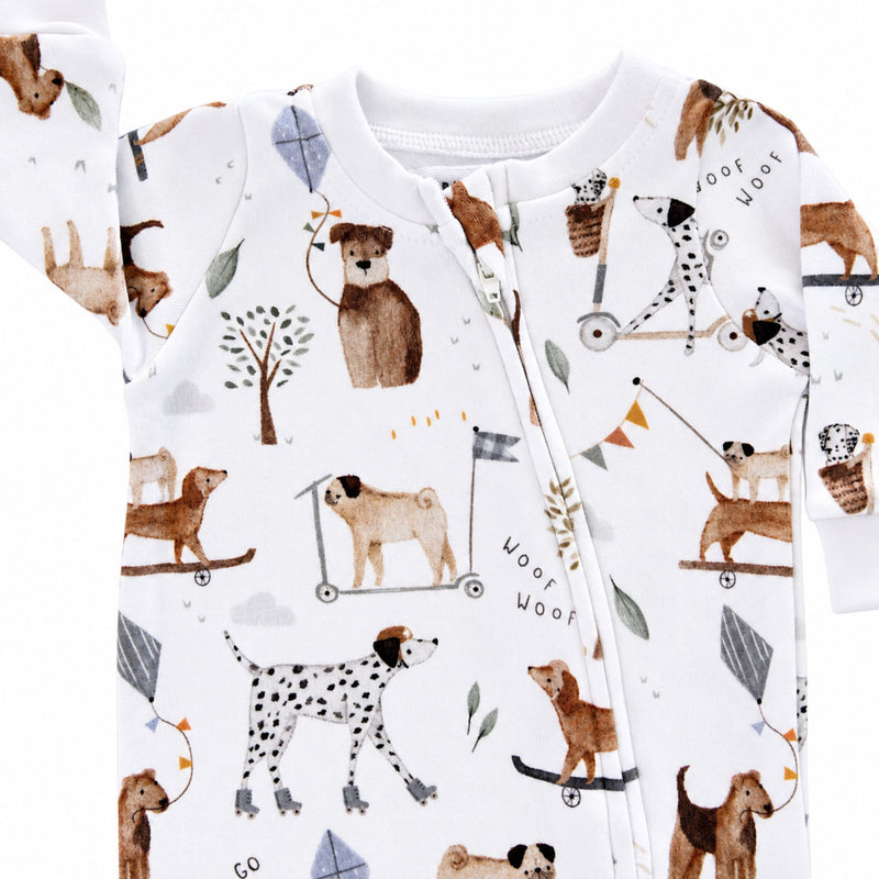Close-up of the Dogs Playground Footy Romper neckline, showing the white ribbed trim, concealed full-length zip and detailed dog, scooter, kite and tree illustrations.
