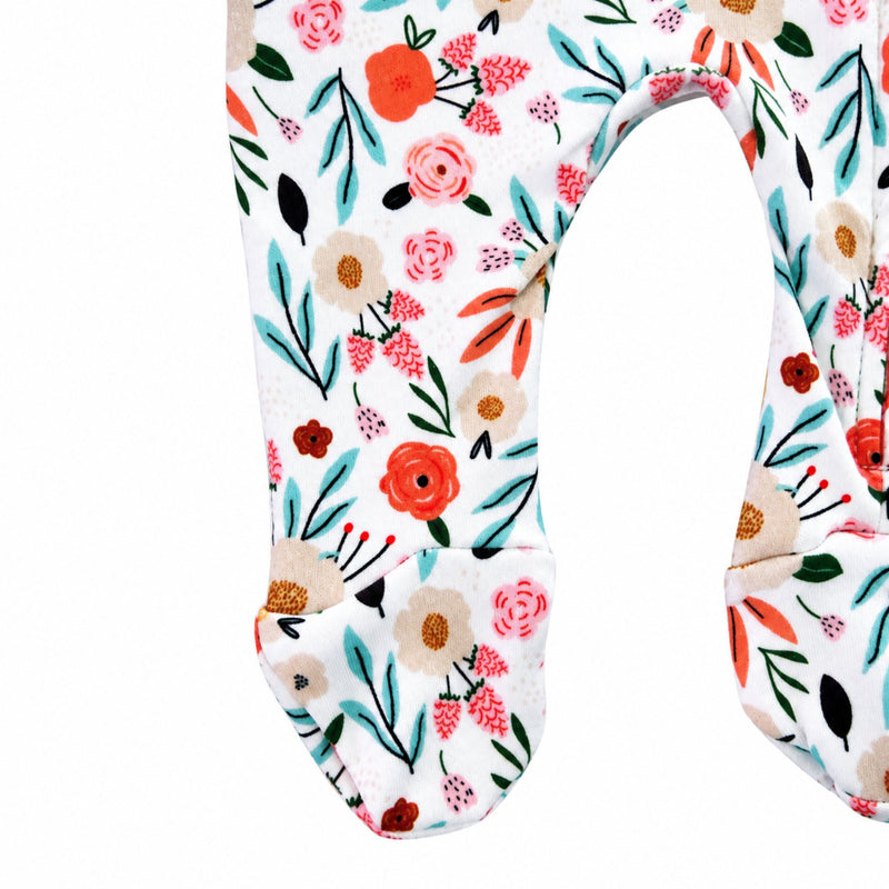 Close-up of the built-in footies on the Oh So Pretty Footy Romper, featuring colourful flowers, leaves and botanical details on white cotton fabric.