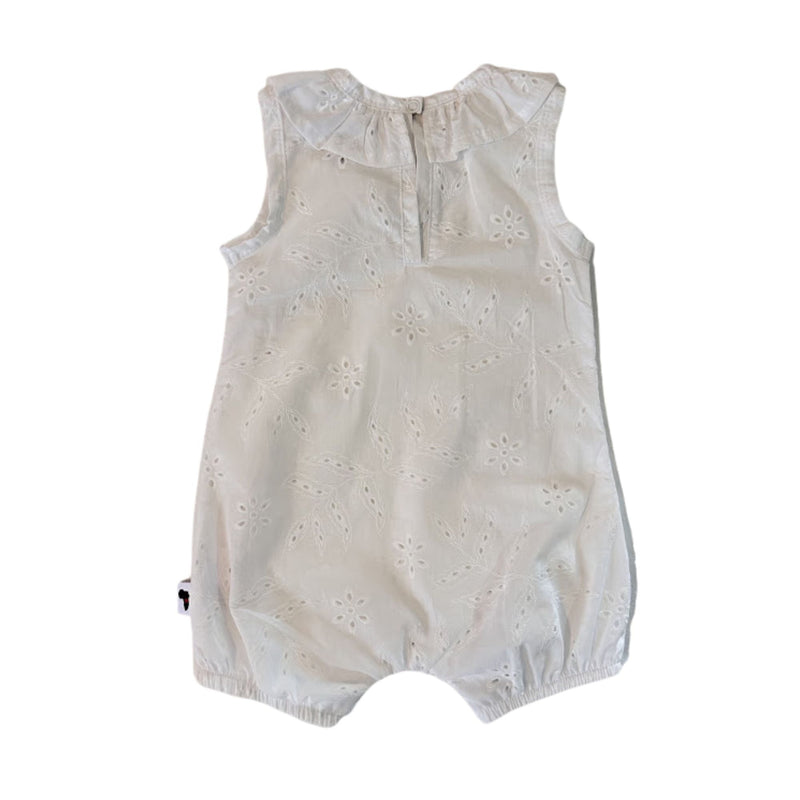 Back view of the white broderie anglaise baby romper, showing the sleeveless shape, keyhole opening and single press-stud fastening at the neckline.