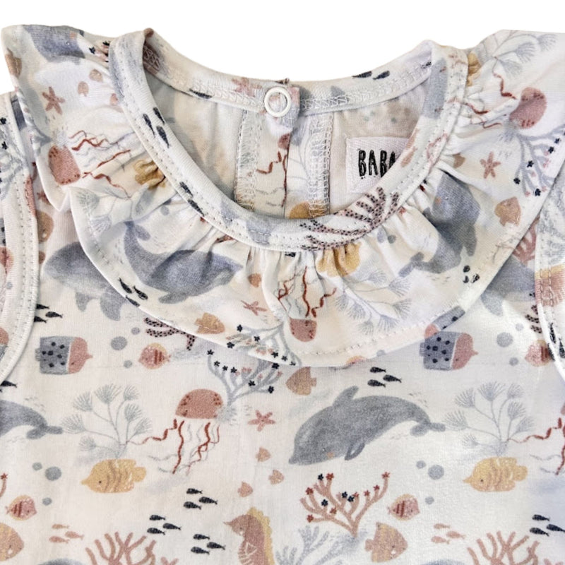 Front neckline close-up of the Two By Two Frilly Neck Romper showing the gathered frill collar and detailed dolphins and sea-life print