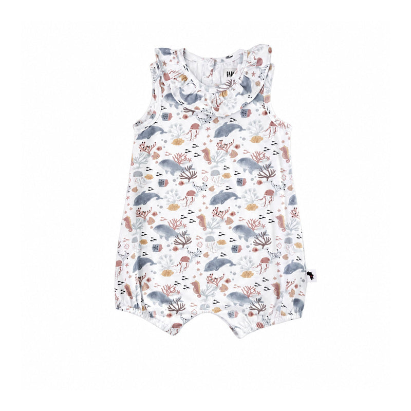 A sleeveless baby romper with a ruffled collar, featuring an all-over dolphins and sea life print in muted gray, brown, and beige tones on a white background.