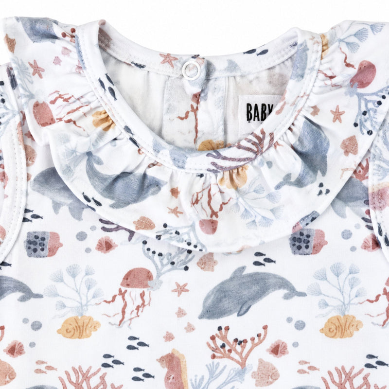 Front neckline close-up of the Two By Two Frilly Neck Romper showing the gathered frill collar and detailed dolphins and sea-life print