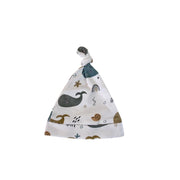 A baby beanie with a knotted top, featuring a white background with a whimsical pattern of a dark gray whale, a brown snail, a small rainbow, and scattered gold stars.