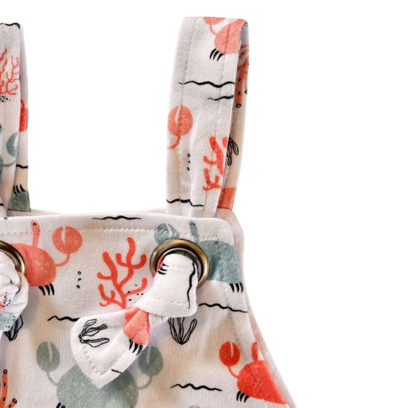 Knot view  of Knot Dungaree - Crab Gang in white background with pink and pale blue crabs print, sea-inspired details and knot shoulder straps
