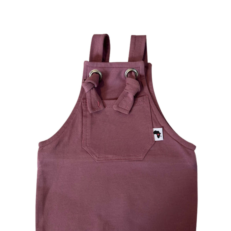 Closeup of A grape coloured knot dungaree long leg with adjustable shoulder straps and a front pocket with a small white Baba Fishees brand tag.
