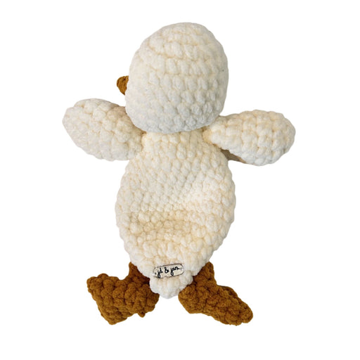 Back view of a crocheted plush duck toy with a textured cream body, a mustard yellow beak, and mustard yellow webbed feet.