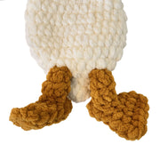 A close-up of a chunky, textured plush toy or stuffed animal showing a large cream body and two mustard-brown feet.