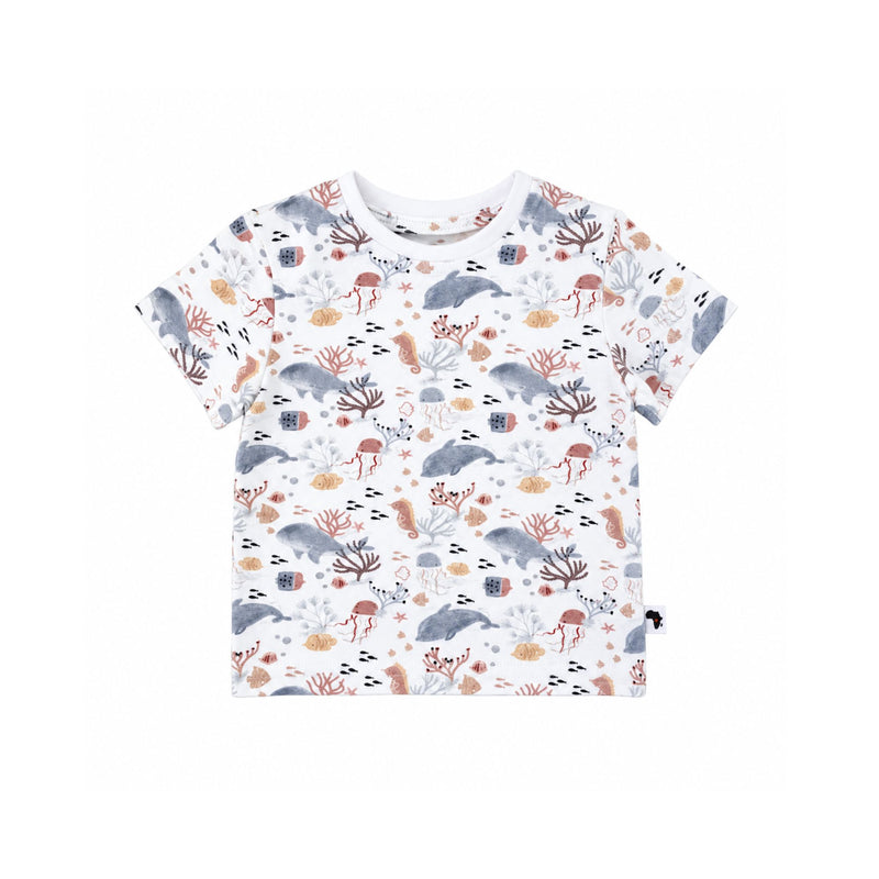A short-sleeve baby and toddler t-shirt with an all-over underwater-themed print featuring dolphins, sea anemones, starfish, and sponges in muted gray, brown, and beige tones on a white background.