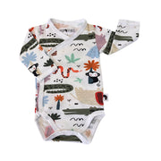 A long-sleeve baby wrap onesie bodysuit with an all-over safari-themed print on a white background. The print features illustrations of [alm trees, a snake, a monkey, a bird, and abstract shapes in muted green, orange, blue, and black.