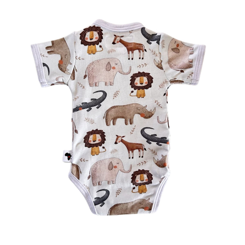 A short-sleeve baby bodysuit with an all-over safari animal print on a white background. The print features watercolor-style illustrations of lions, elephants, rhinos, giraffes, crocodiles, and an okapi in earthy brown, gray, and black tones.