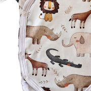Close-up of a baby garment with a white background and an all-over safari animal print featuring a lion, rhinoceros, elephant, giraffe, crocodile, and leaves. The garment has white snap closures along the left edge.