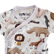 A close-up of a baby wrap-style romper with a white base and a playful safari animal print including a lion, rhinoceros, elephant, giraffe, and crocodile. The brand label 'BABA + FISHEES' is visible inside the collar.