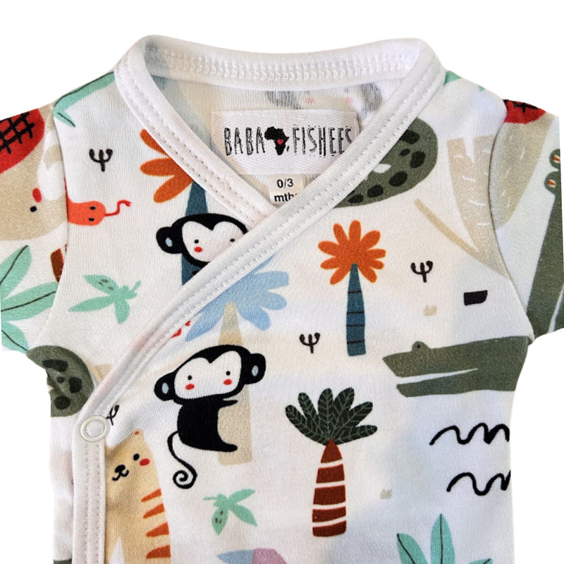 A close-up of a baby wrap onesie with a colorful cartoon animal and plant print on a white background. The brand label 'BABA FISHEES' is visible inside the collar.