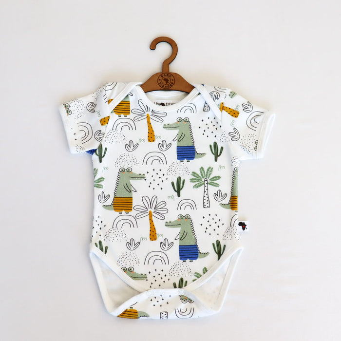 A soft, high-quality short sleeve cotton classic onesie featuring illustrations of a walking crocodile and palm trees and doodles.