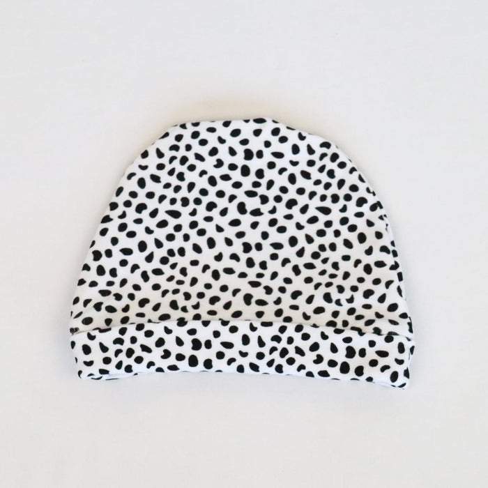 A white classic baby beanie with black splots.