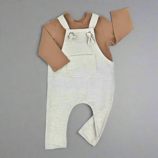 Long knot dungarees in oatmeal colour with long sleeved brown tee shirt underneath.